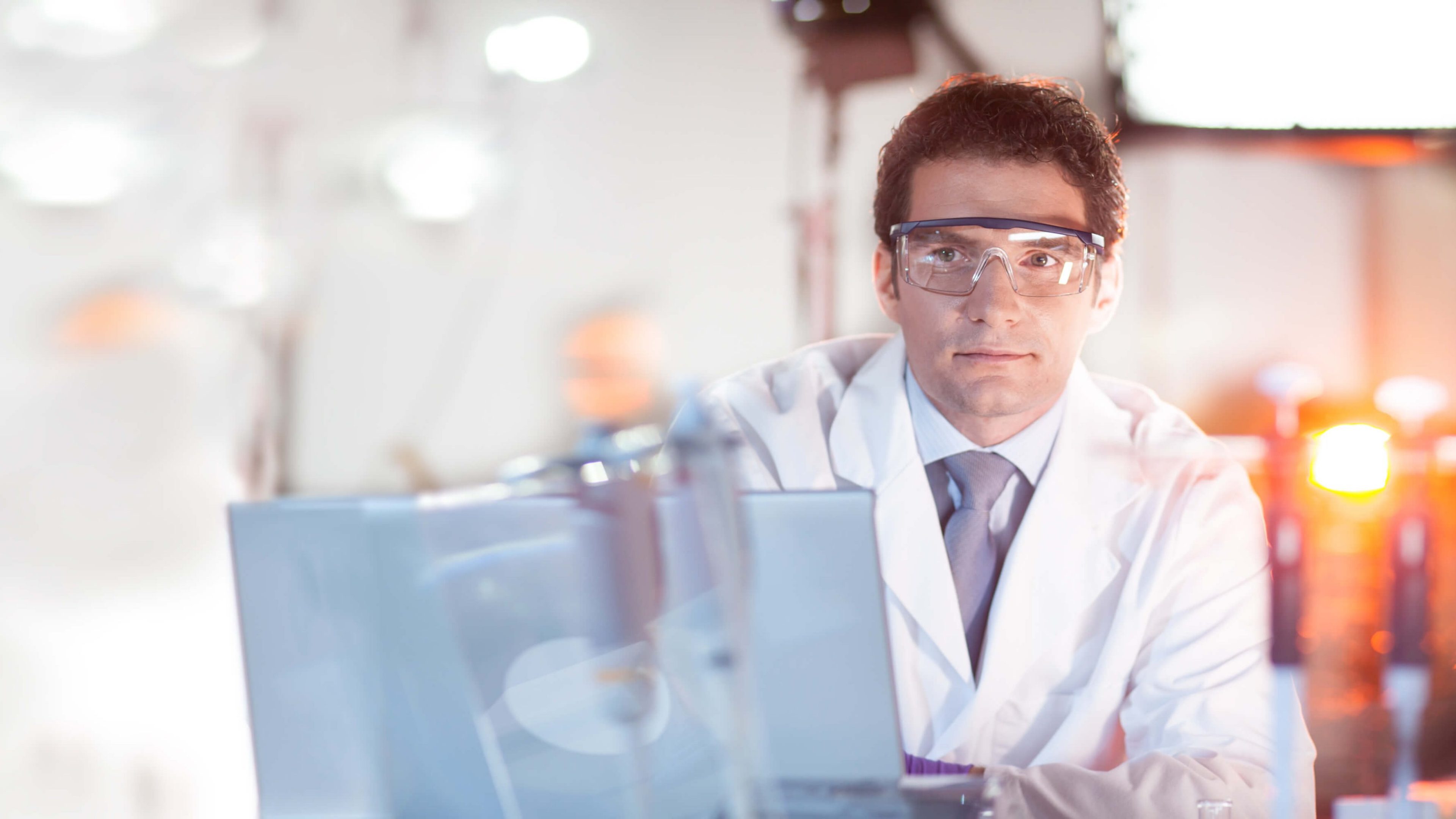 Mann im Labor mit Schutzbrille und Blick in die Kamera
