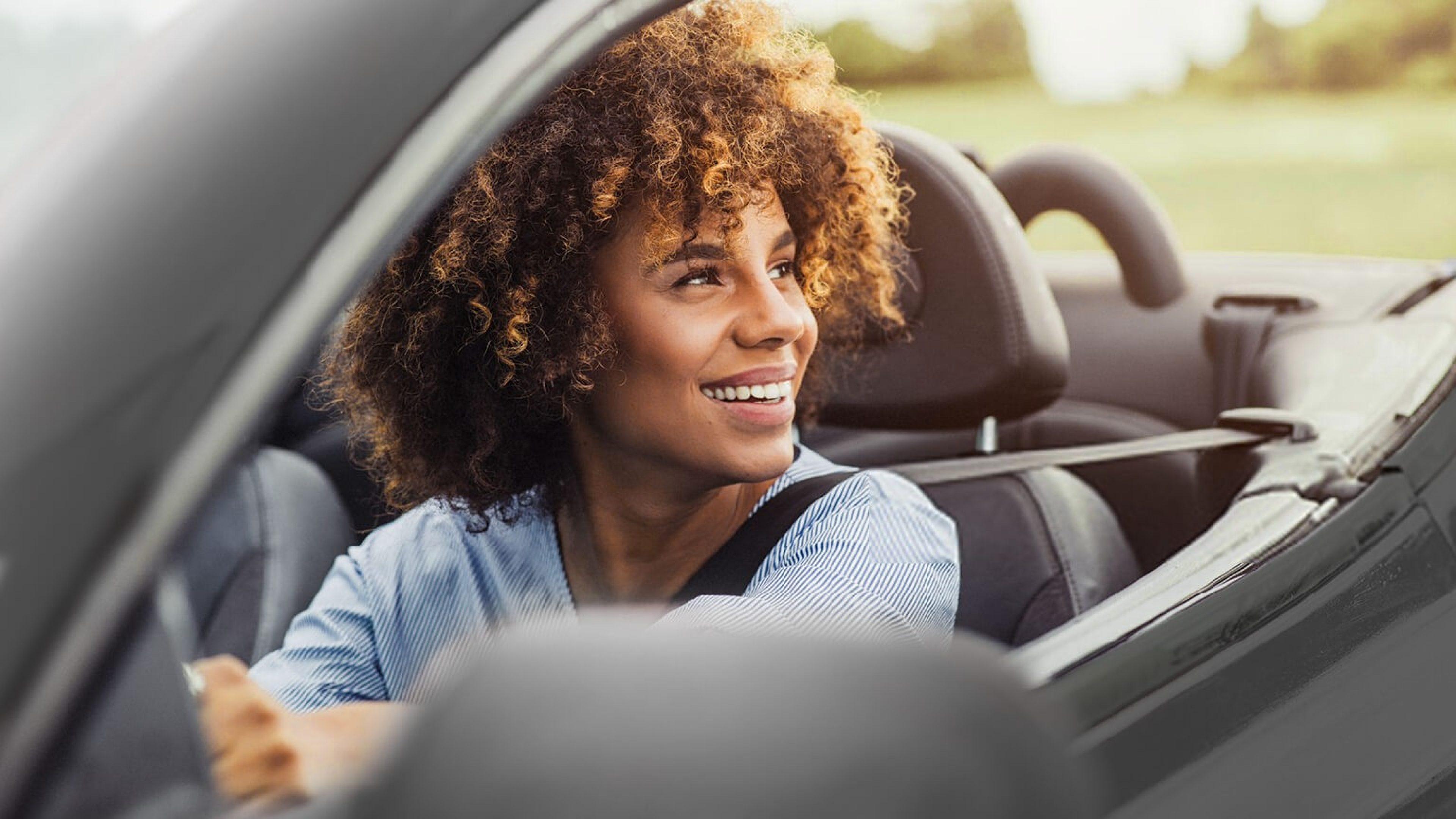 Junge Frau im Elektroauto blickt in die Ferne