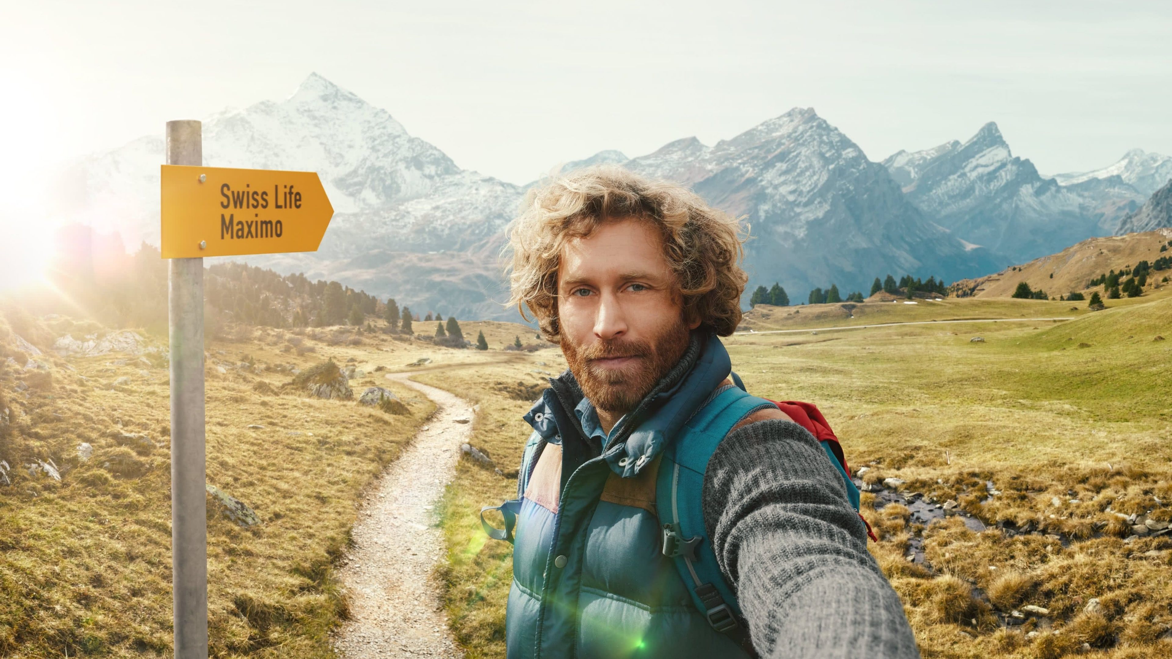 Junger Mann blickt in Kamera und wandert in den Schweizer Bergen