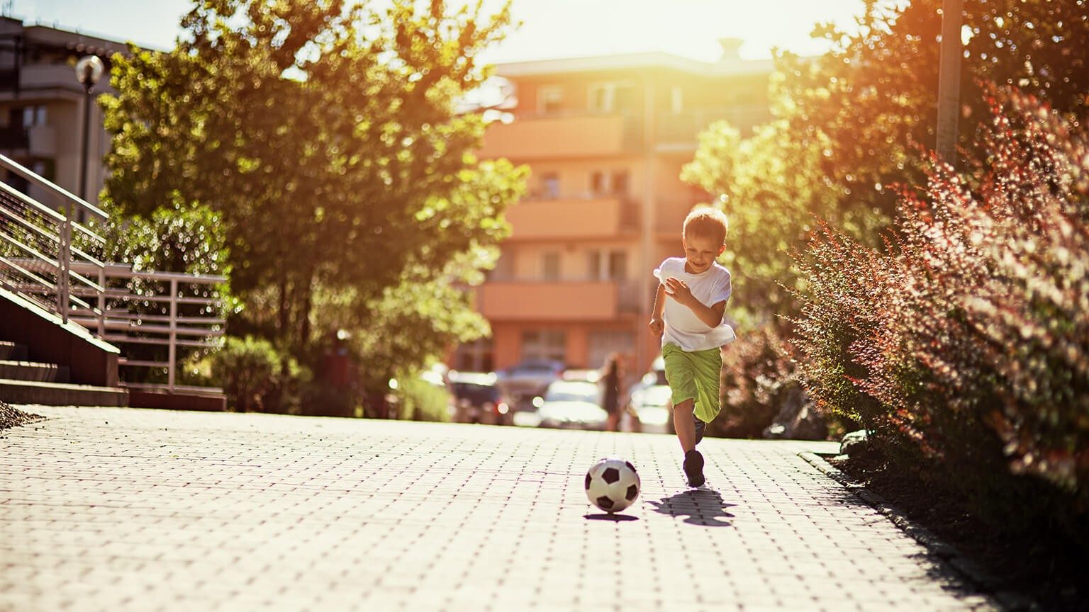 Junge läuft auf der Auffahrt hinter einem Fußball her 