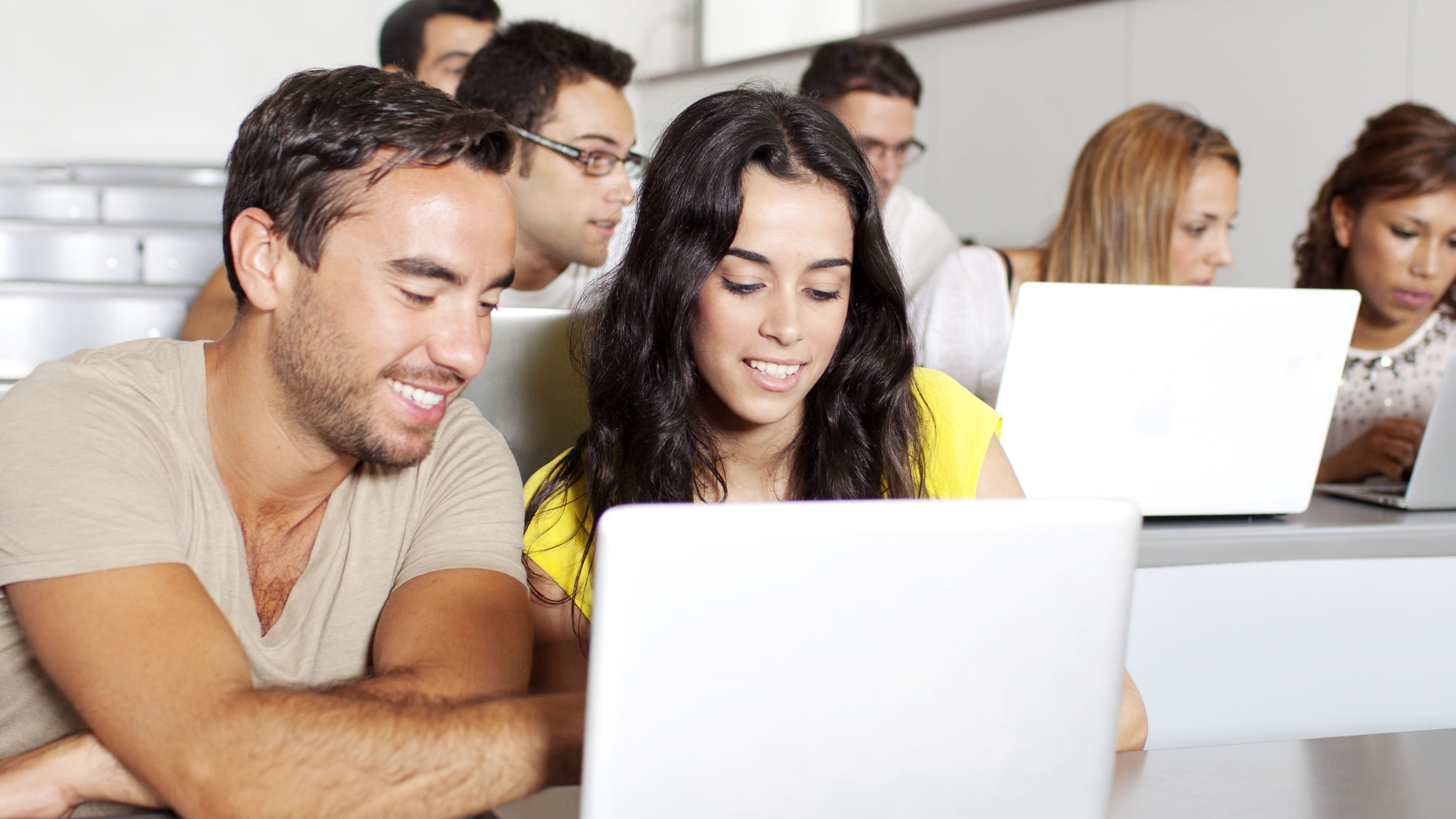 Studenten in einem Hörsaal blicken in den Laptop