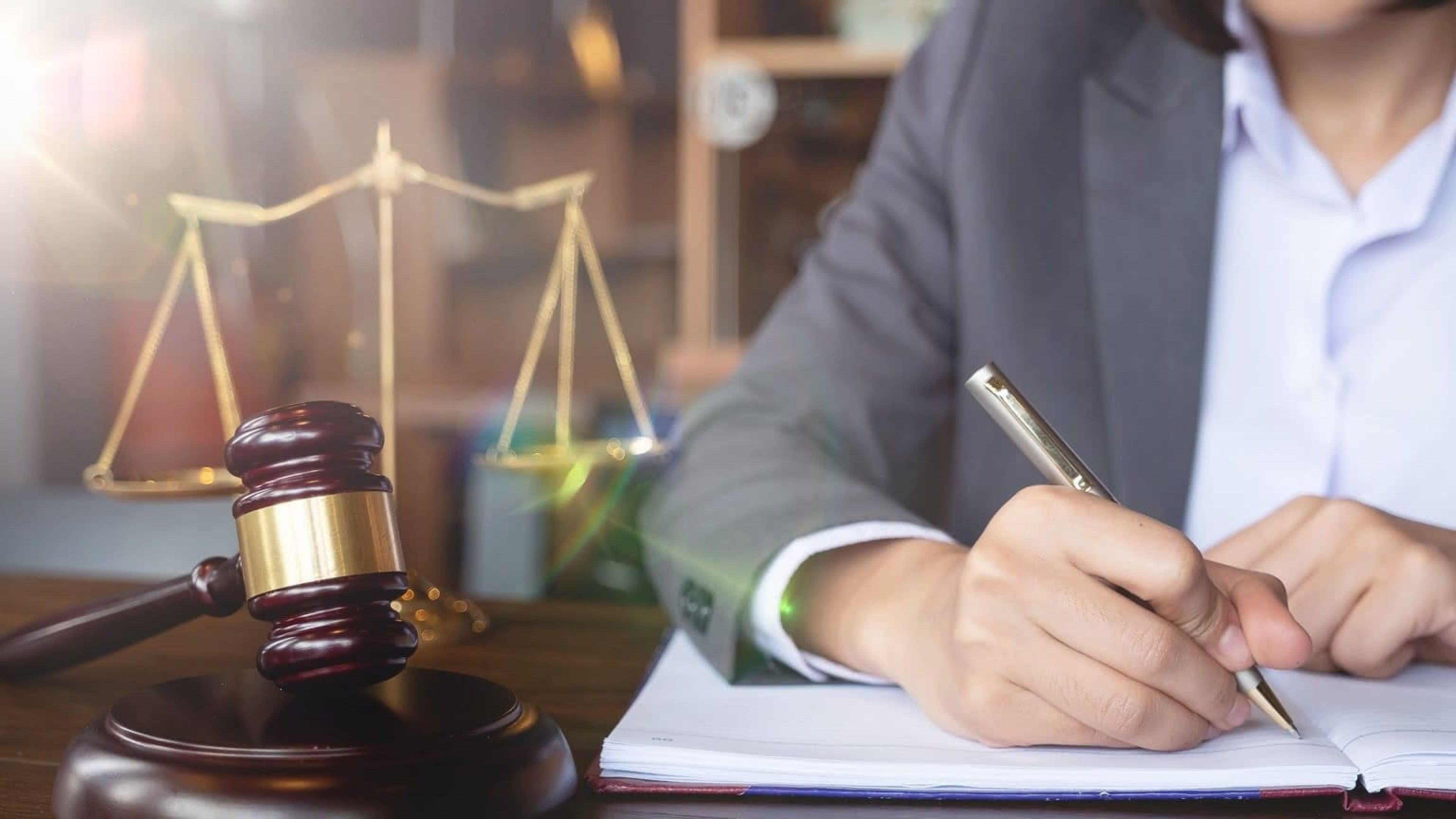 Rechtsschutzversicherung Waage auf Schreibtisch Mann in Anzug unterschreibt Unterlage