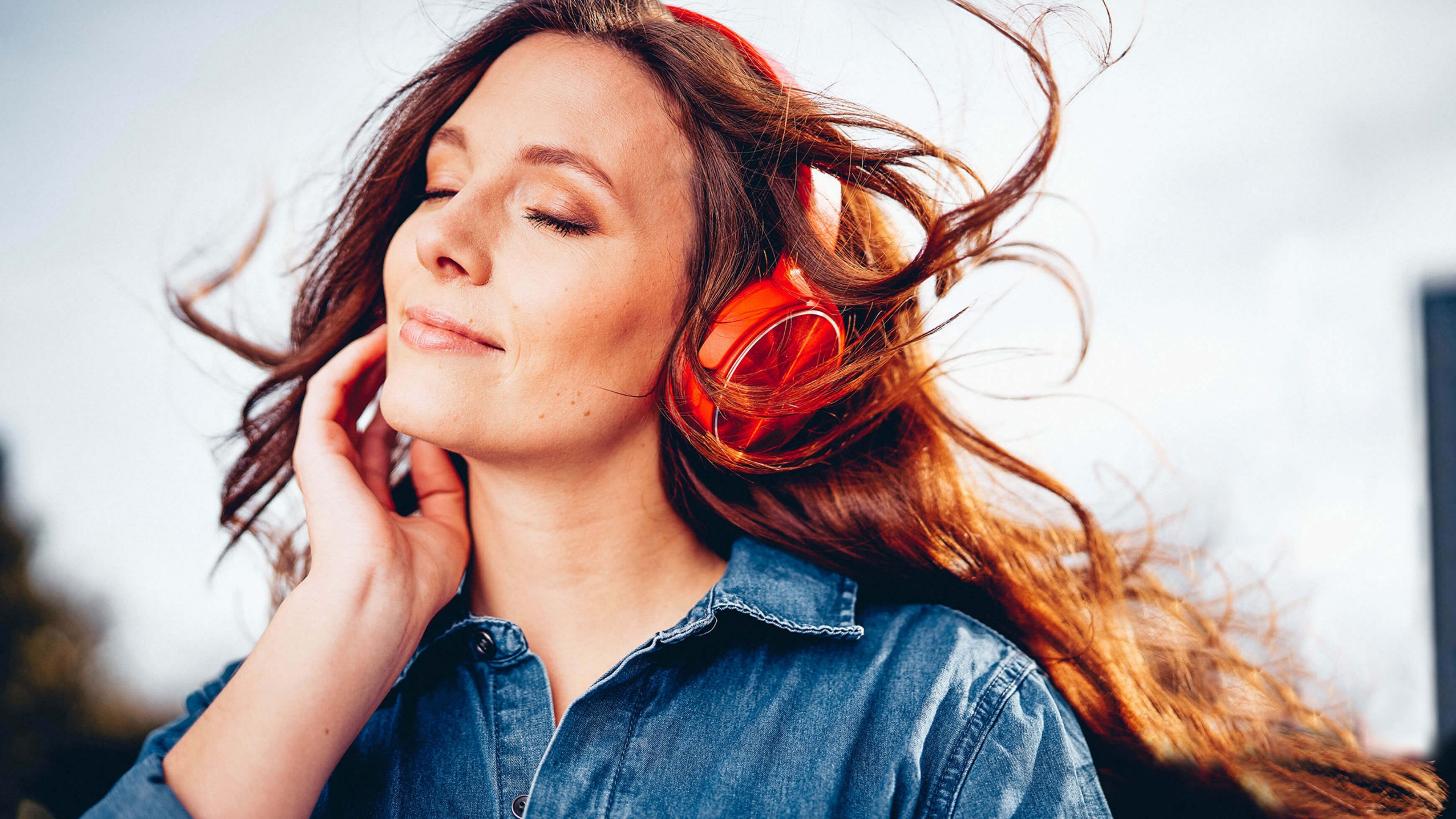 Junge Frau mit roten Swiss Life Kopfhöreren hört Musik