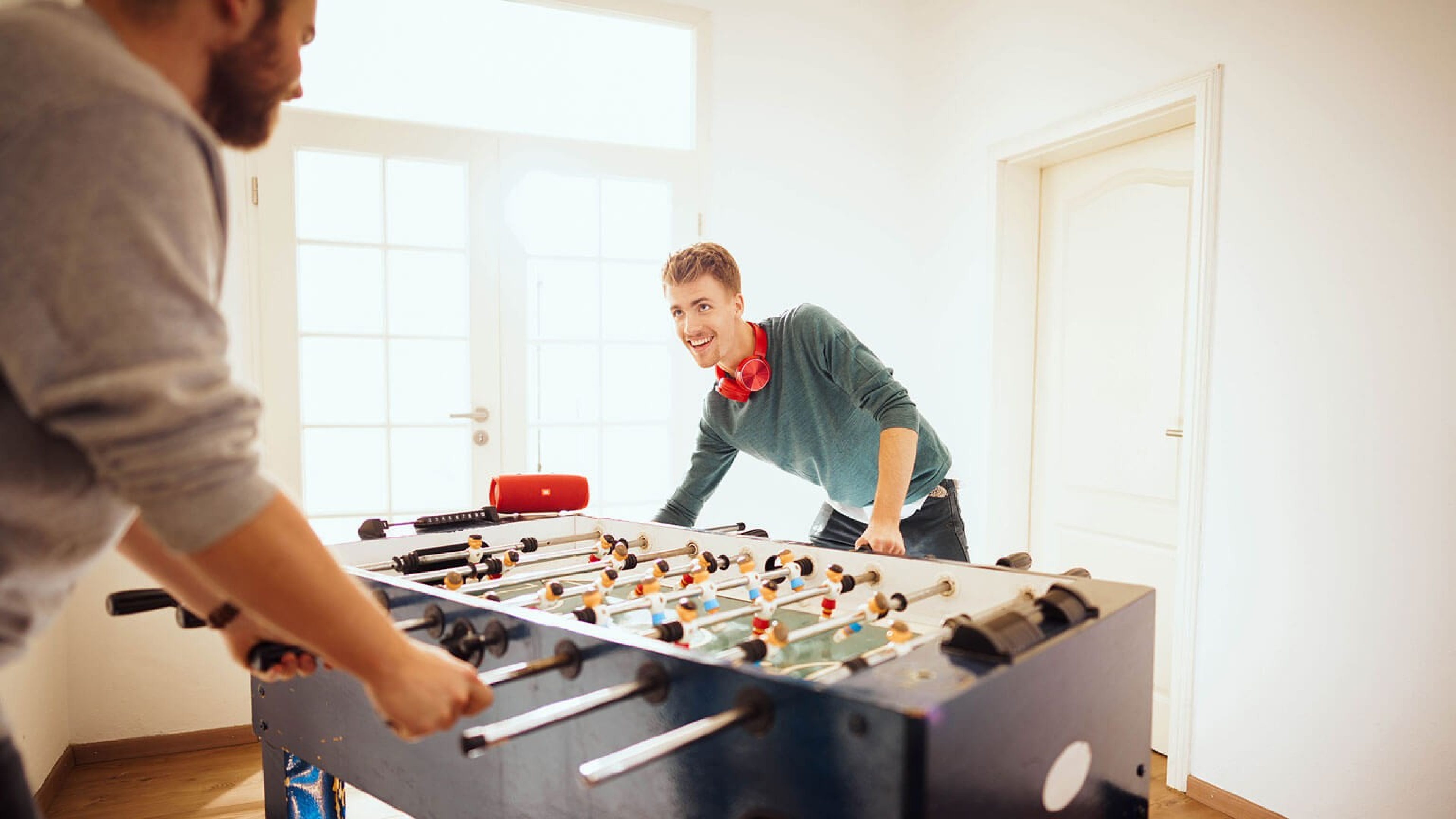 Student mit roten Swiss Life Kopfhörern beim Kickern