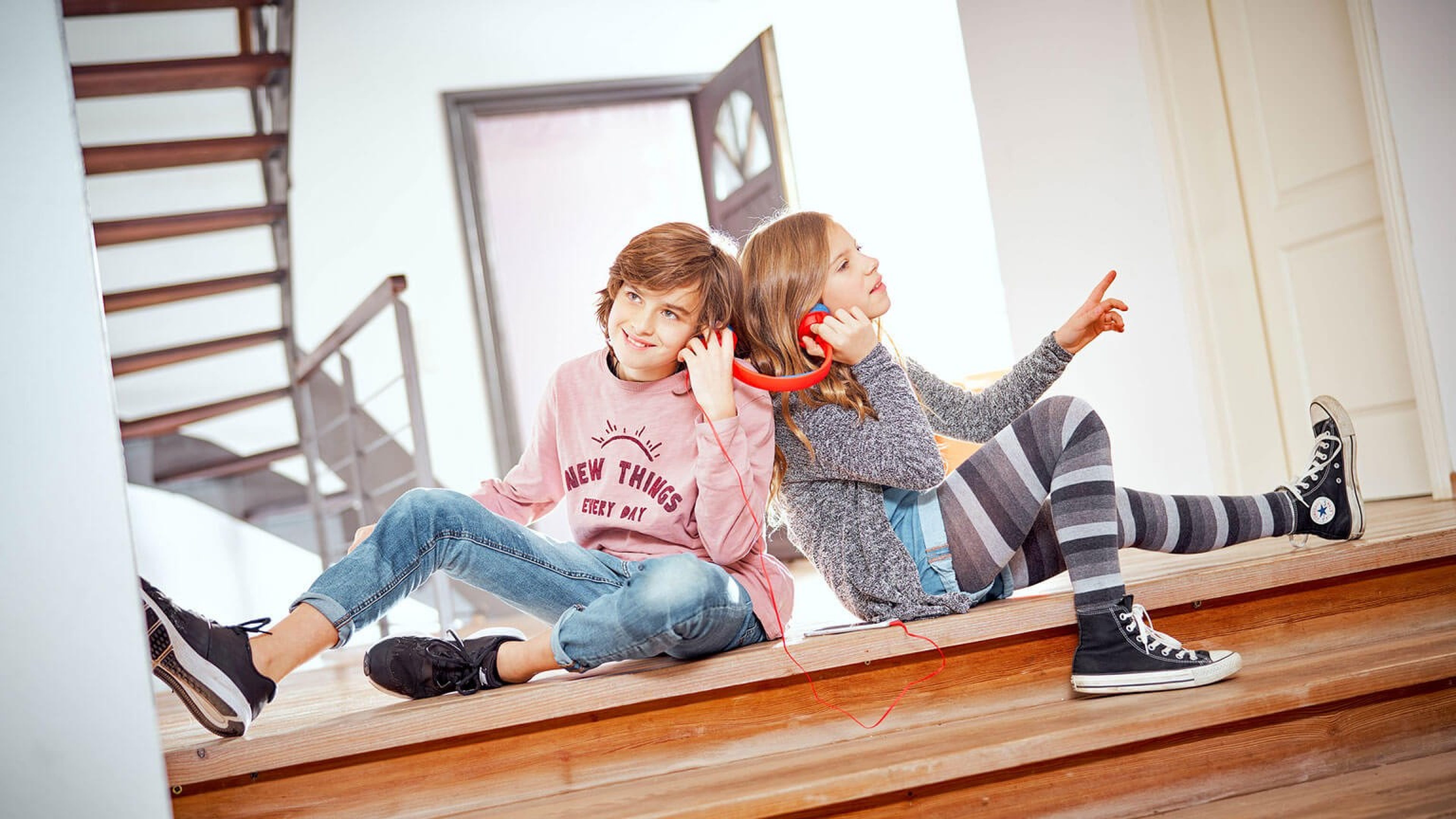 Zwei Schüler sitzen am Boden und teilen sich einen Kopfhörer