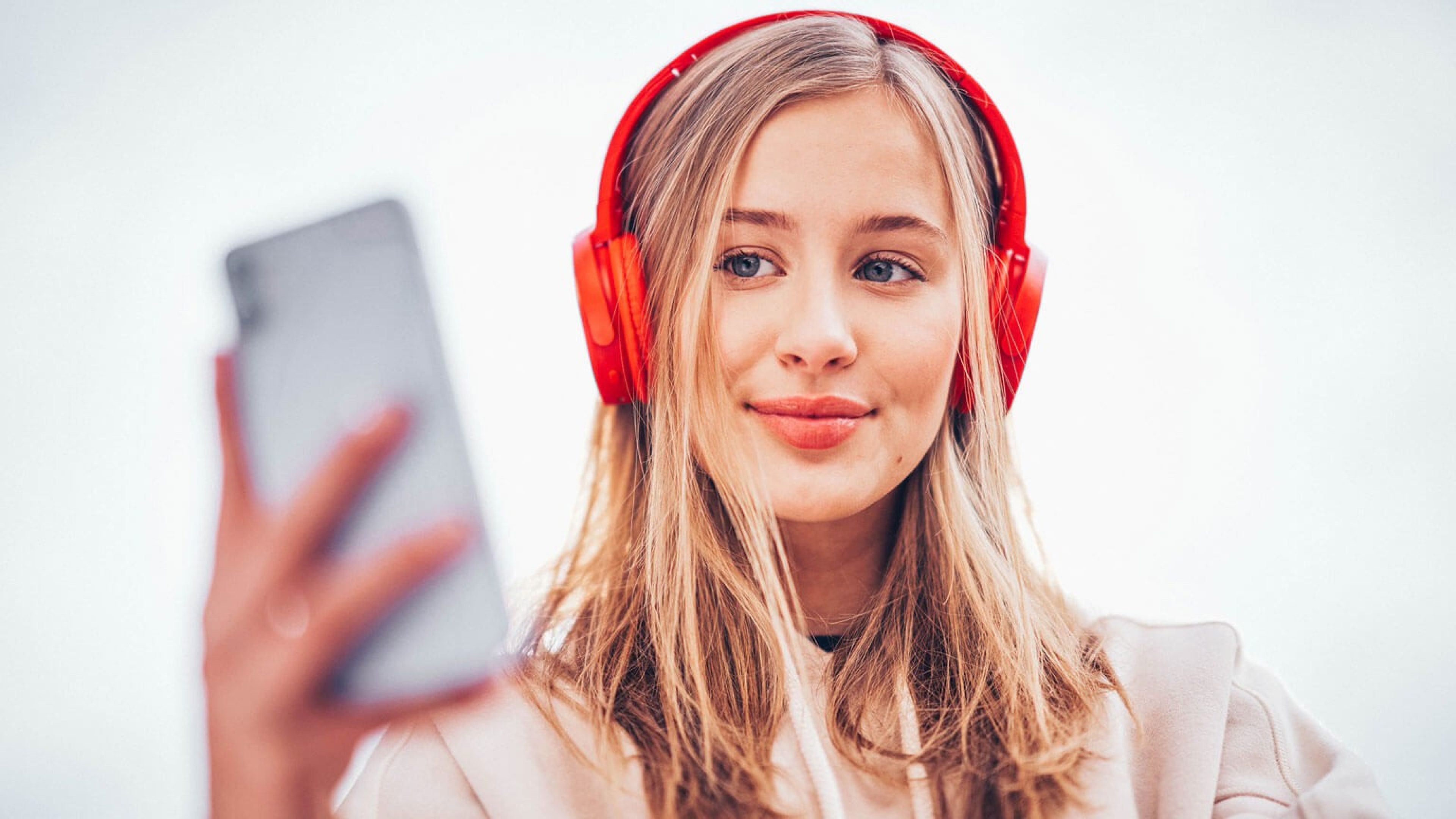 Azubine mit roten Swiss Life Kopfhöreren blickt auf ihr Handy