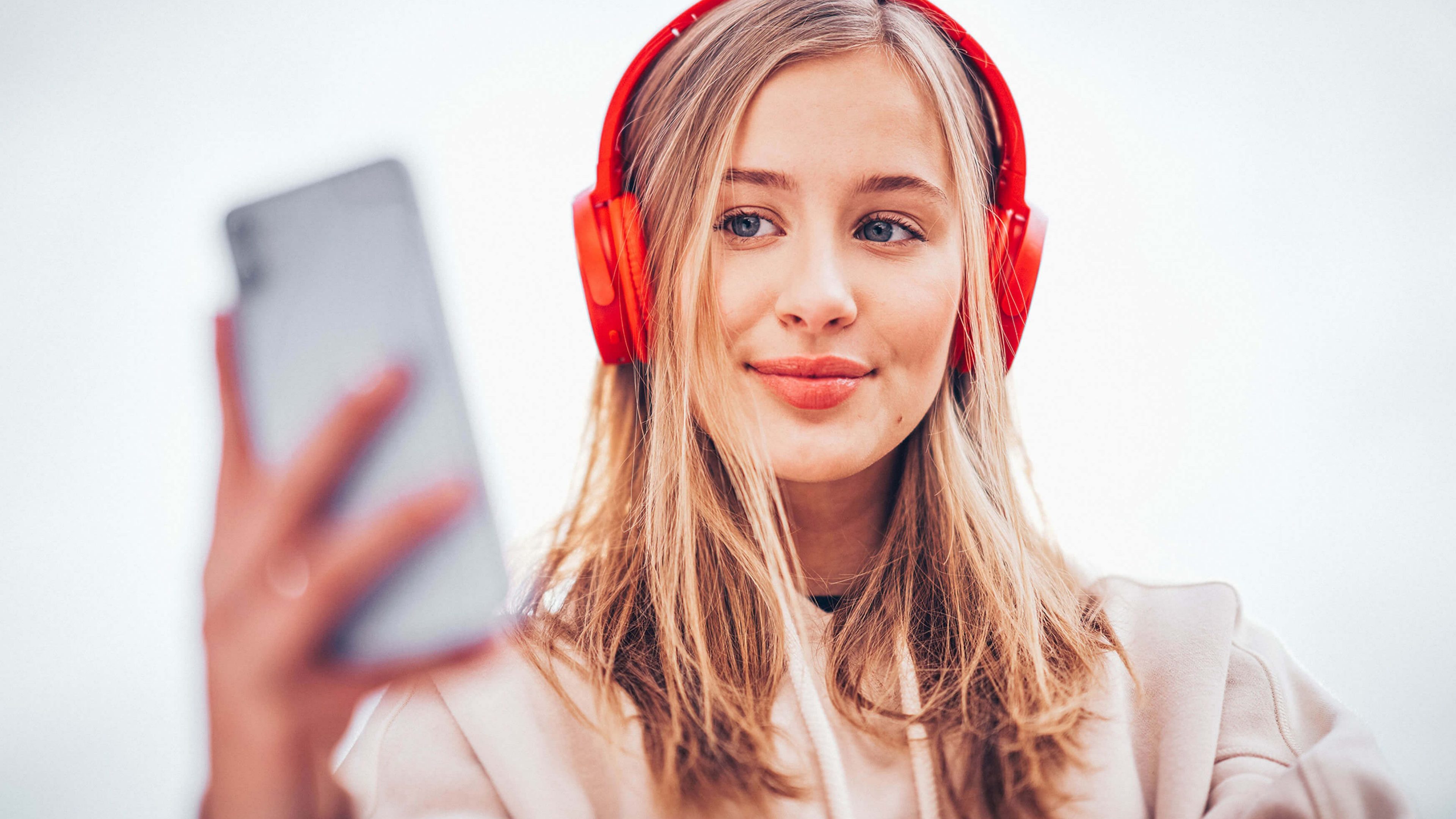 Azubine mit roten Swiss Life Kopfhörern blickt in das Handy
