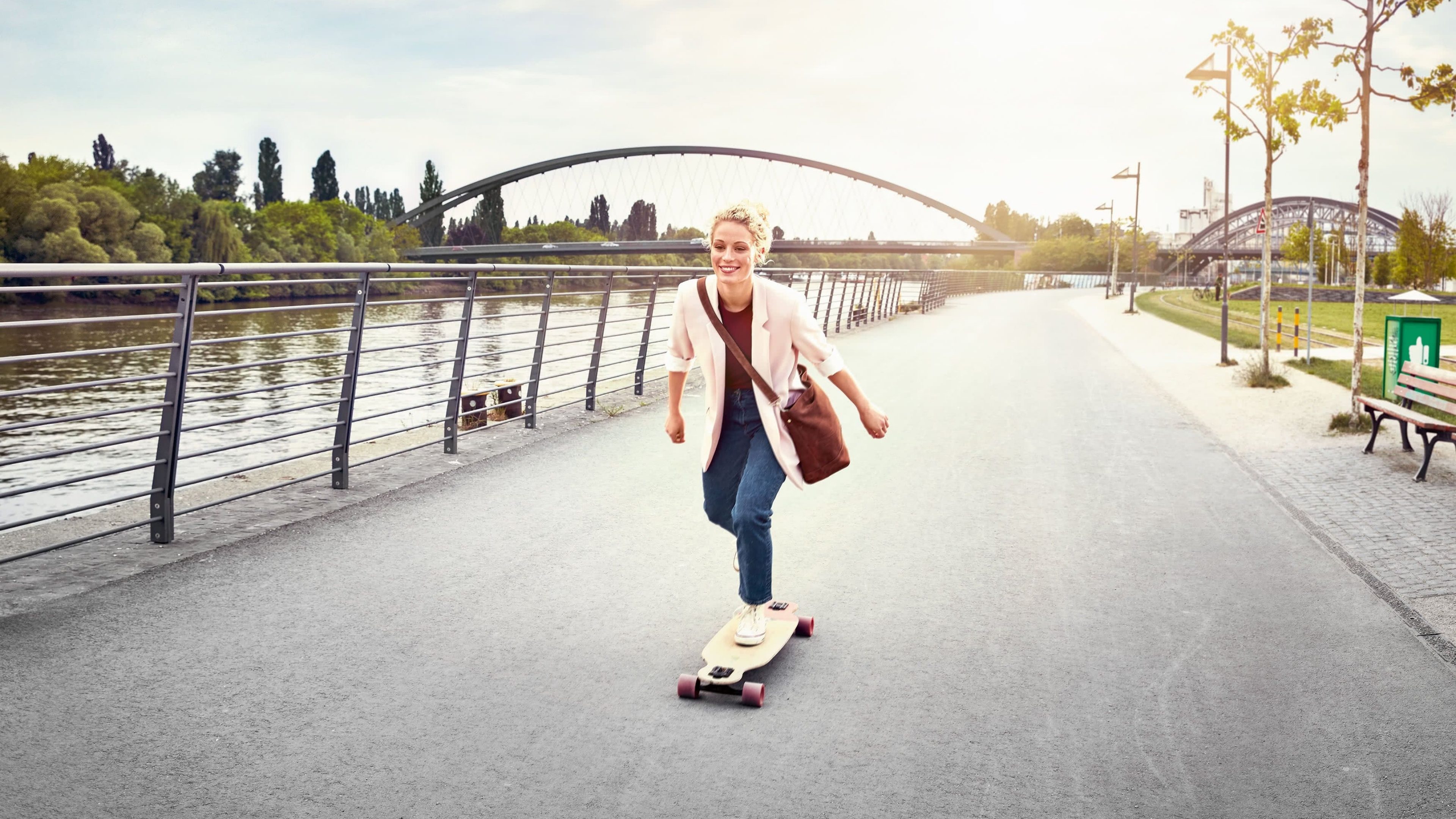 Junge Frau fährt am Fluss Skateboard