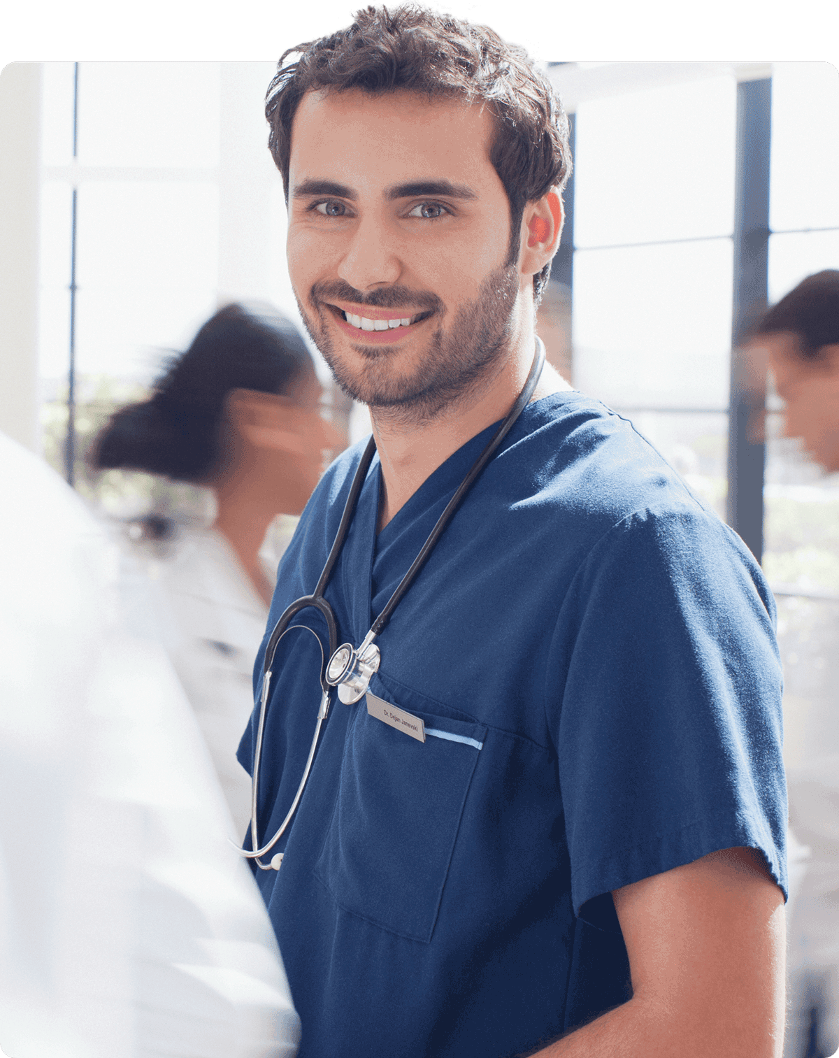 Pflegehelfer in blauen Kittel mit Blick in die Kamera