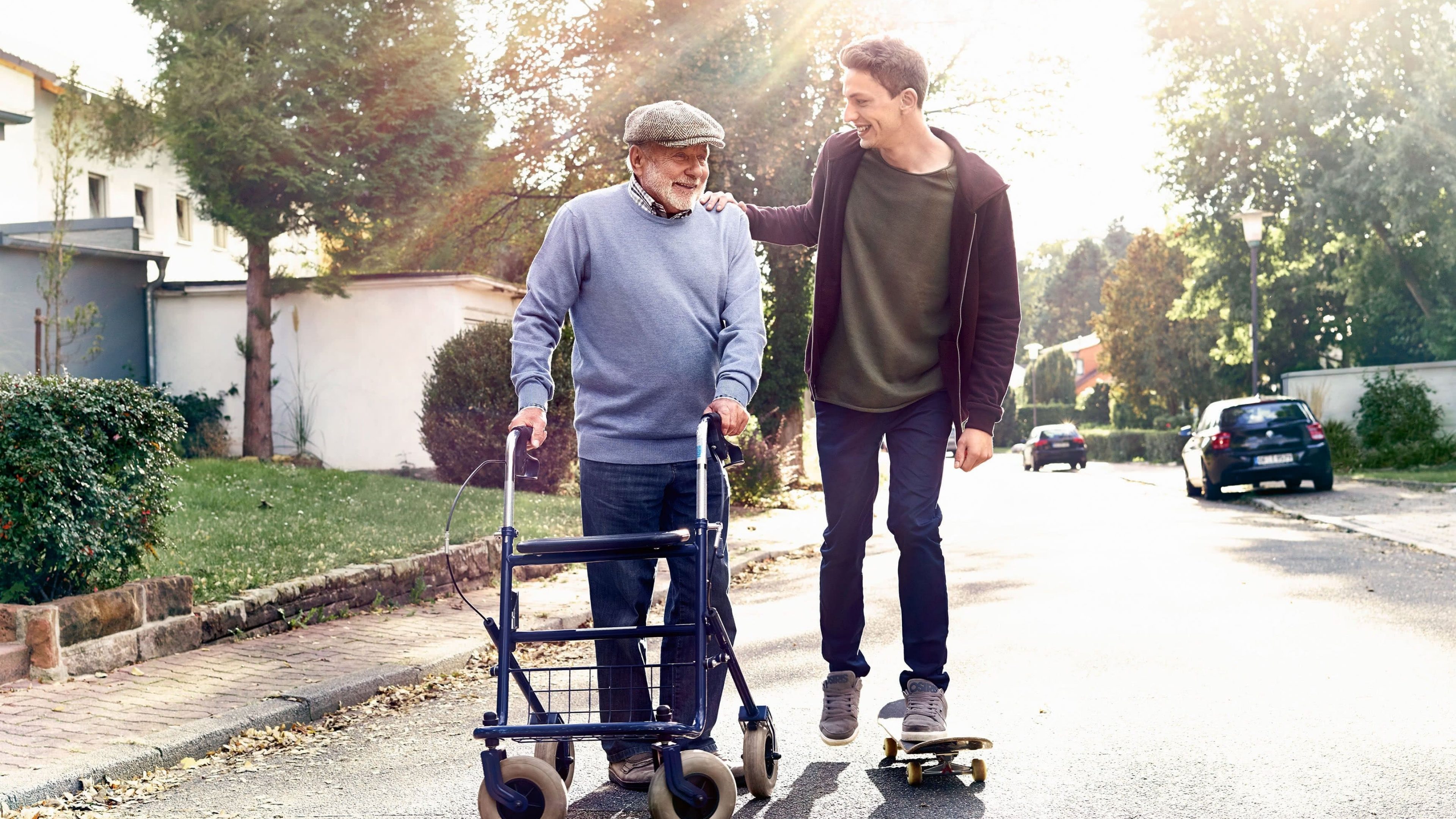 Junger Man geht mit älteren Herrn mit Rollator spazieren