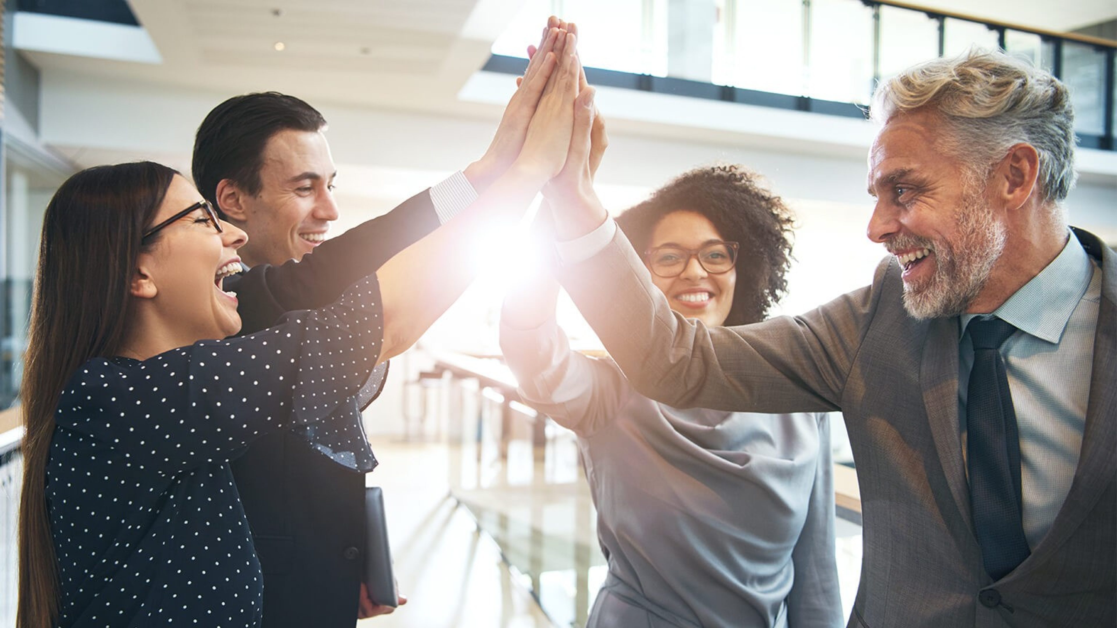 Vier Menschen freuen sich und geben sich gemeinsam High five