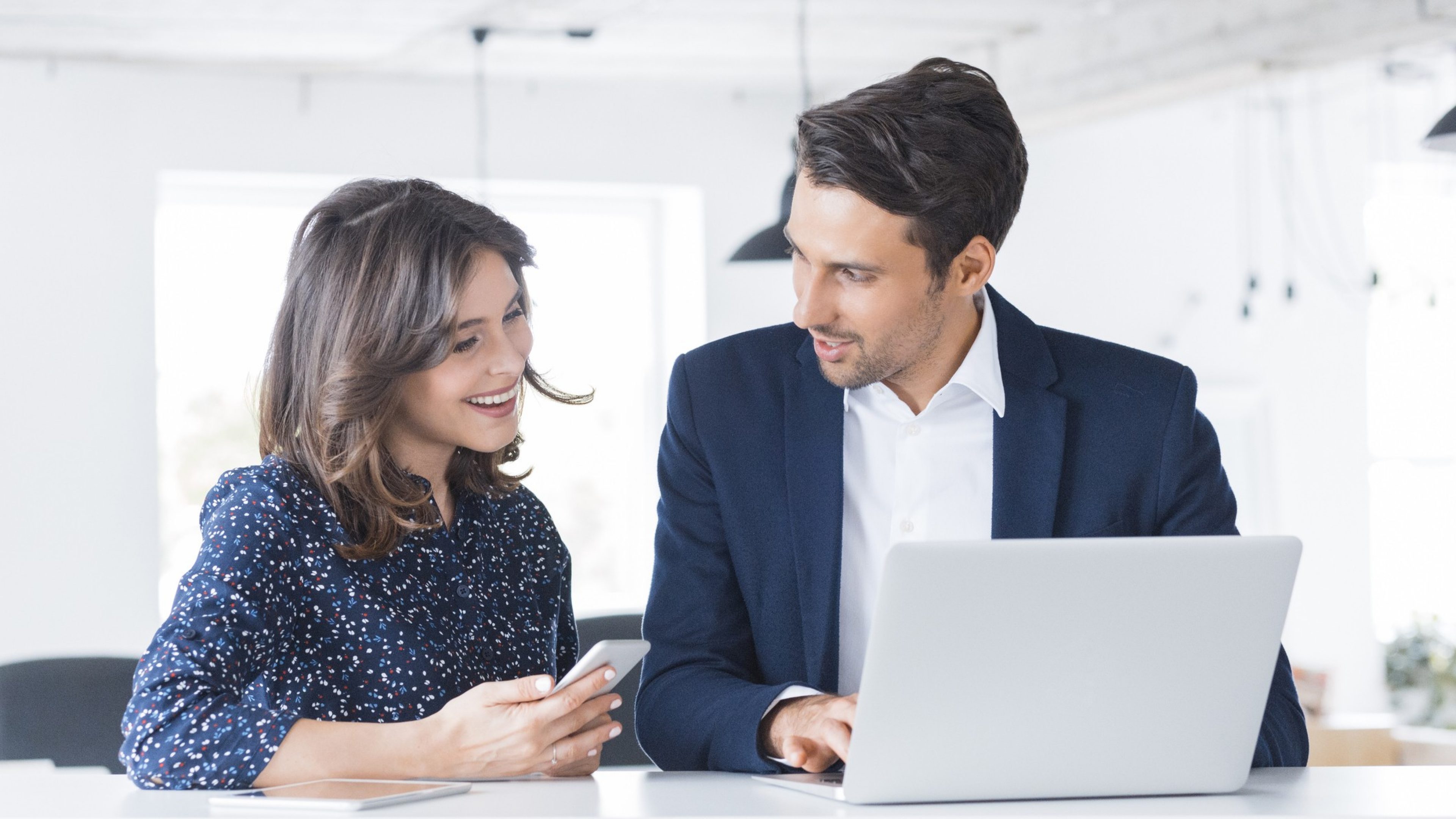 Businessman working on laptop and talking with female colleague. Two business people working together at a startup office.