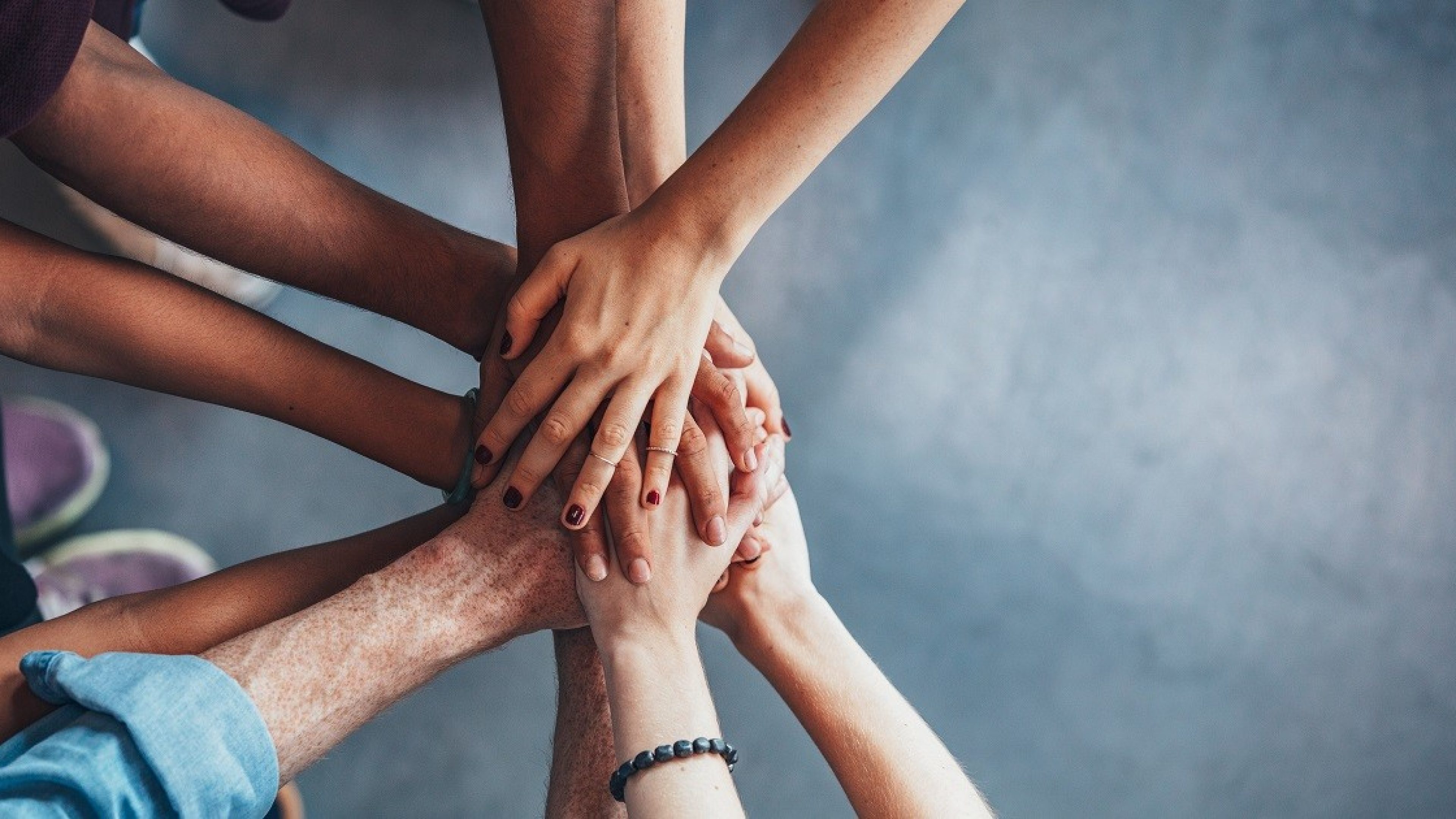 Close up top view of young people putting their hands together. Friends with stack of hands showing unity.