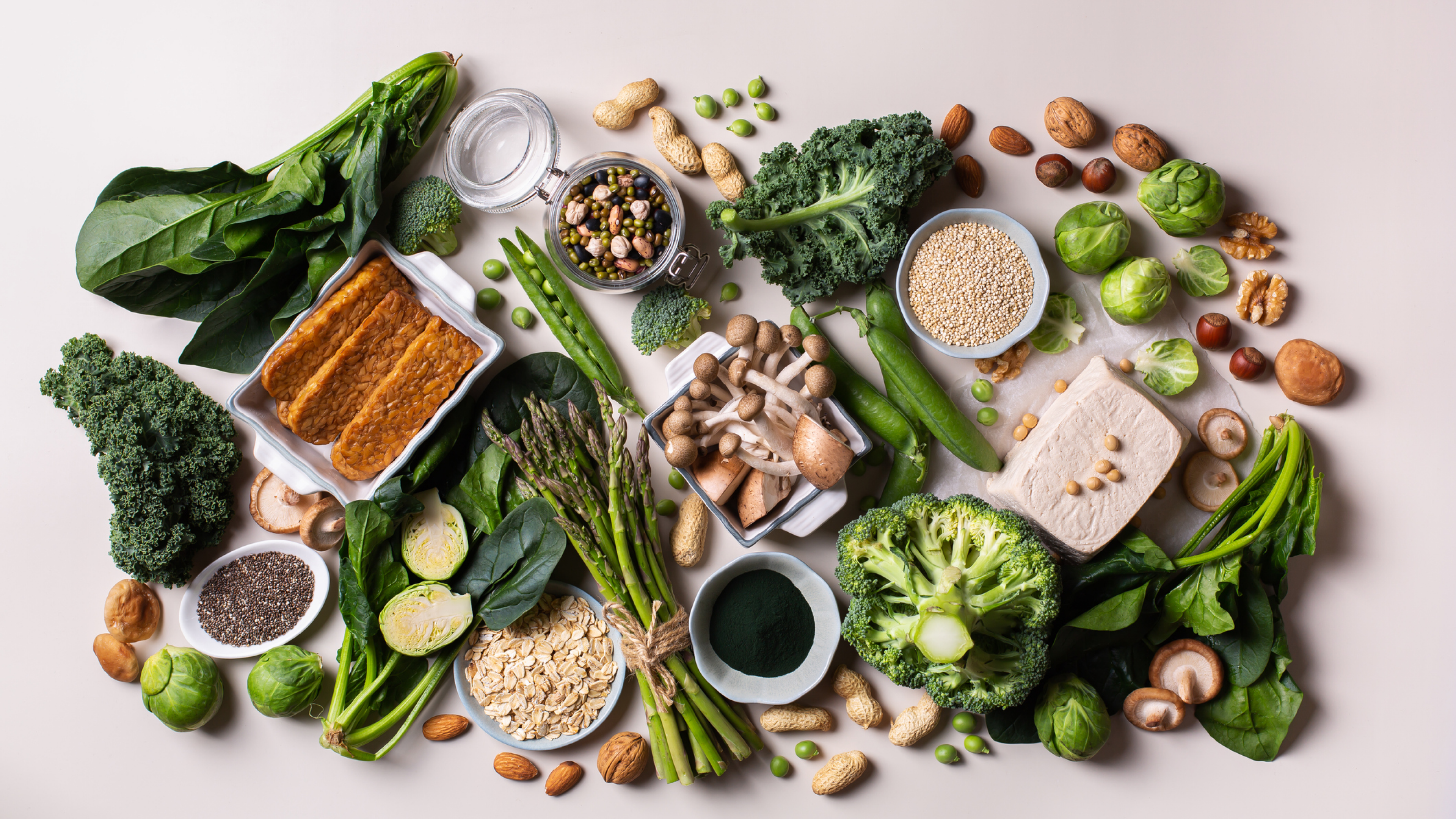 Variety of healthy vegan, plant based protein source and body building food. Tofu soy beans tempeh, green vegetables, nuts, seeds, quinoa oat meal and spirulina. View from above