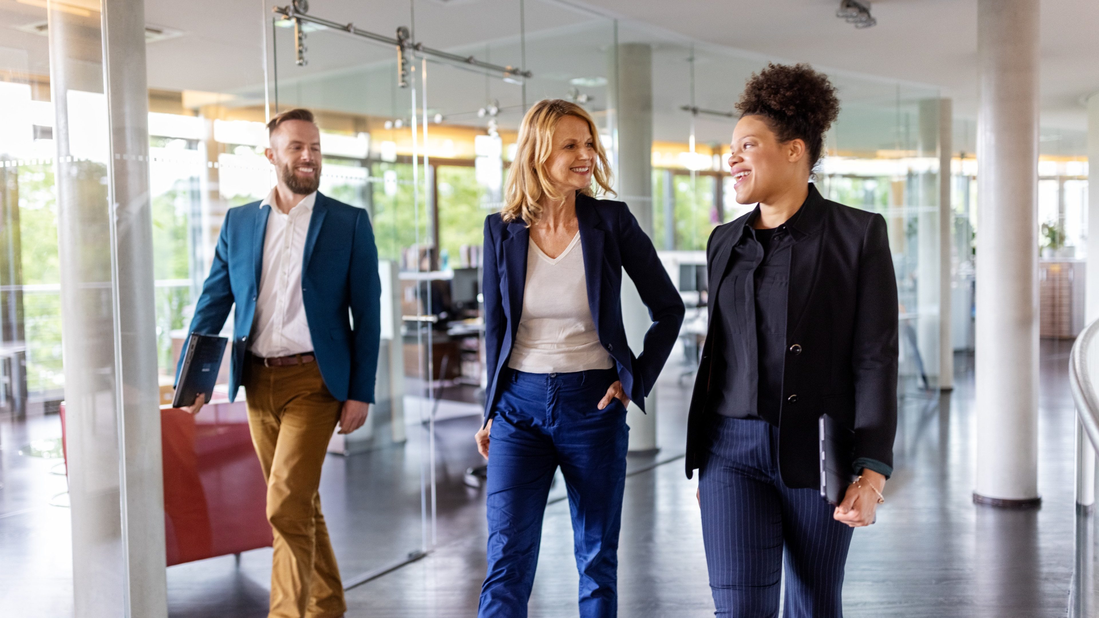 Group of multiracial businesspeople discussing while walking through the office. Team of corporate professionals moving through the office corridor.