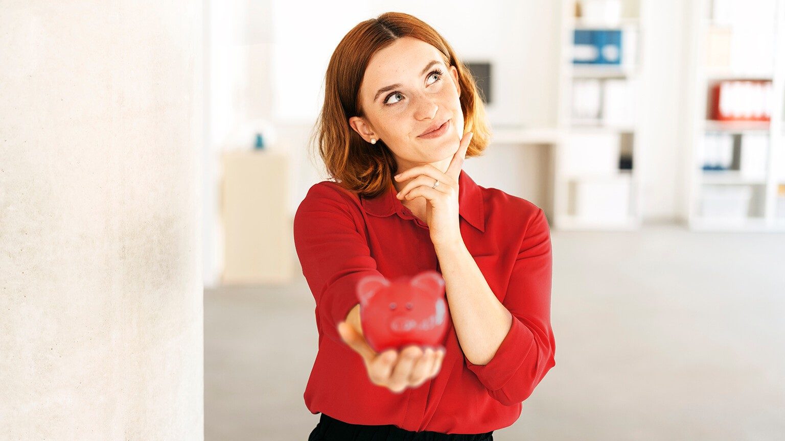 Junge Frau hält ein Sparschwein in der Hand.
