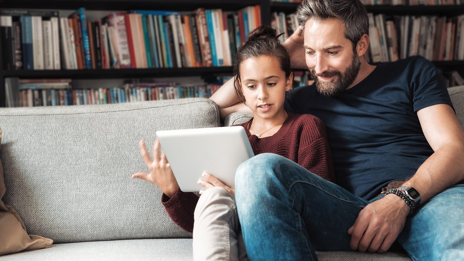 Vater checkt die Hausaufgaben der Tochter auf dem Sofa
