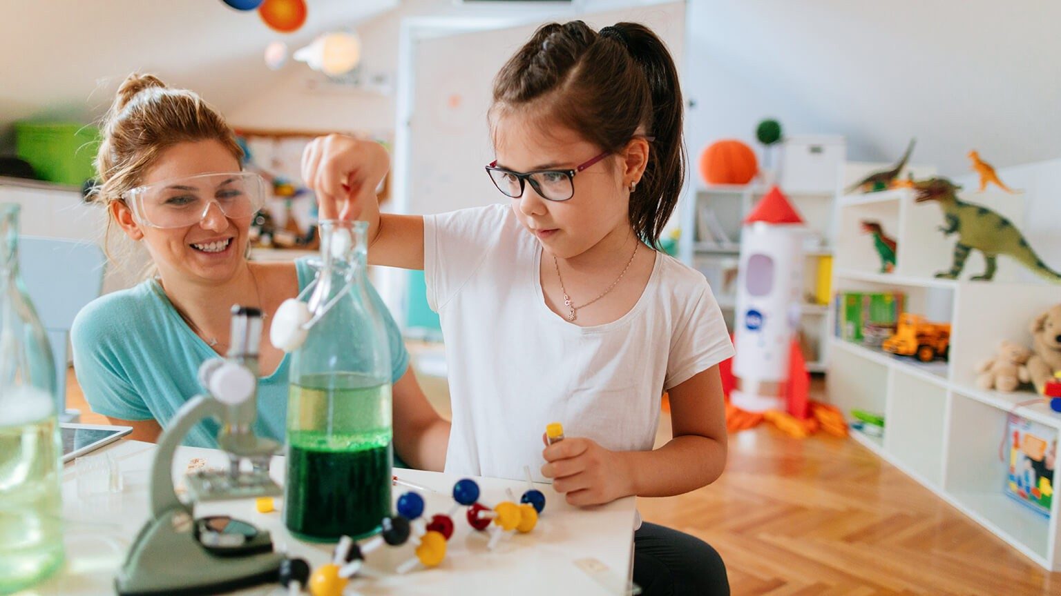 Mutter und Tochter machen ein einfaches Experiment am Schreibtisch